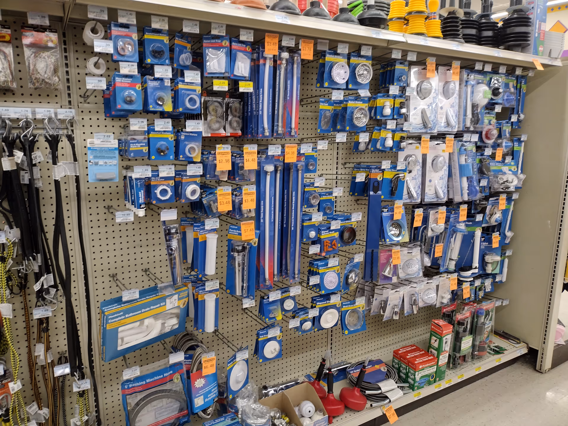 A store aisle filled with blue-packaged plumbing fixtures and shower accessories on pegboard.