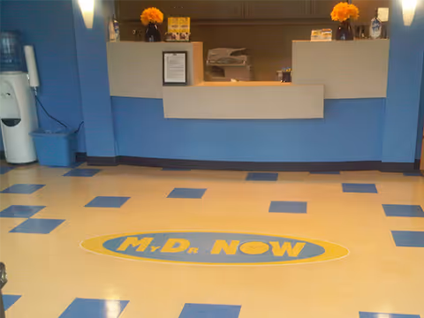 Reception area of a senior facility with blue decor, counter, flowers, and a logo floor decal.