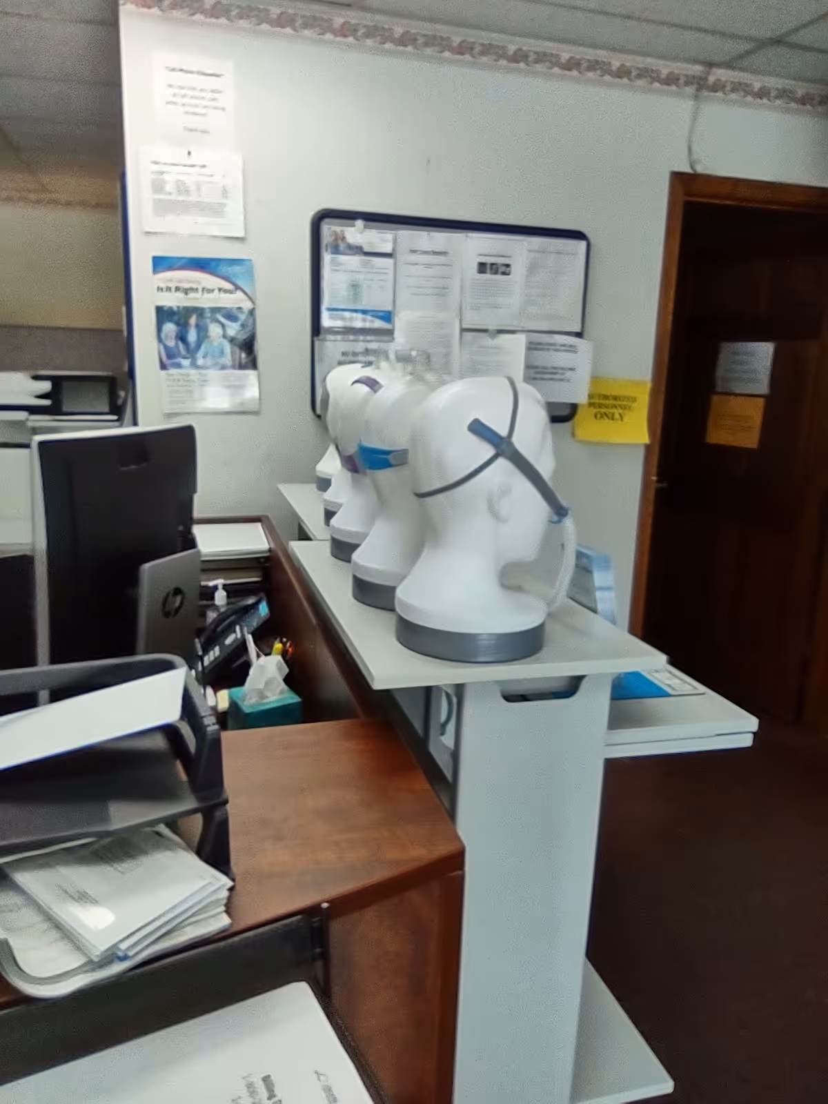 Office reception area with computer, documents, and mannequin heads on the counter.