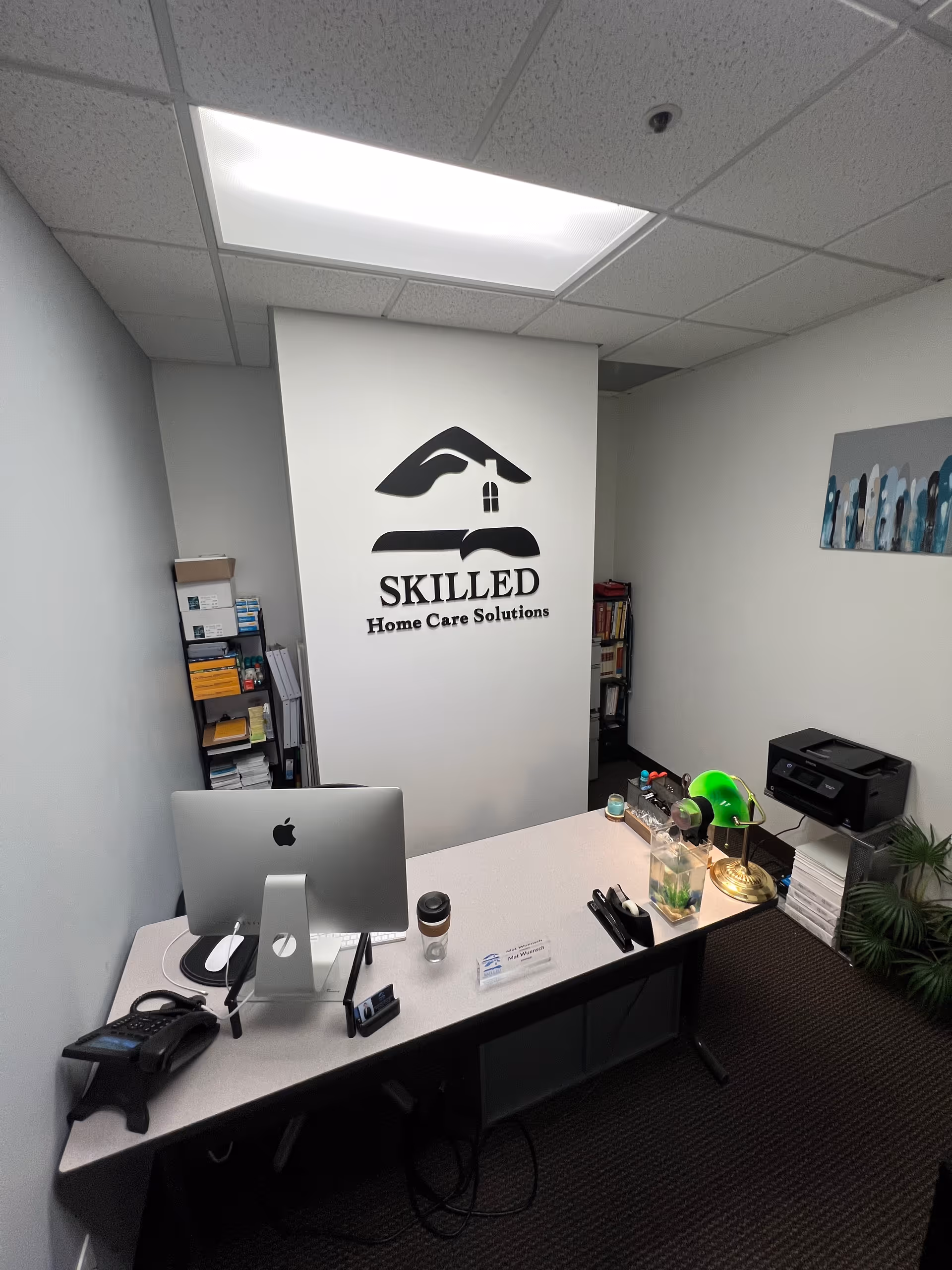 Interior office with desk, computer, and SKILLED Home Care Solutions logo on the wall.