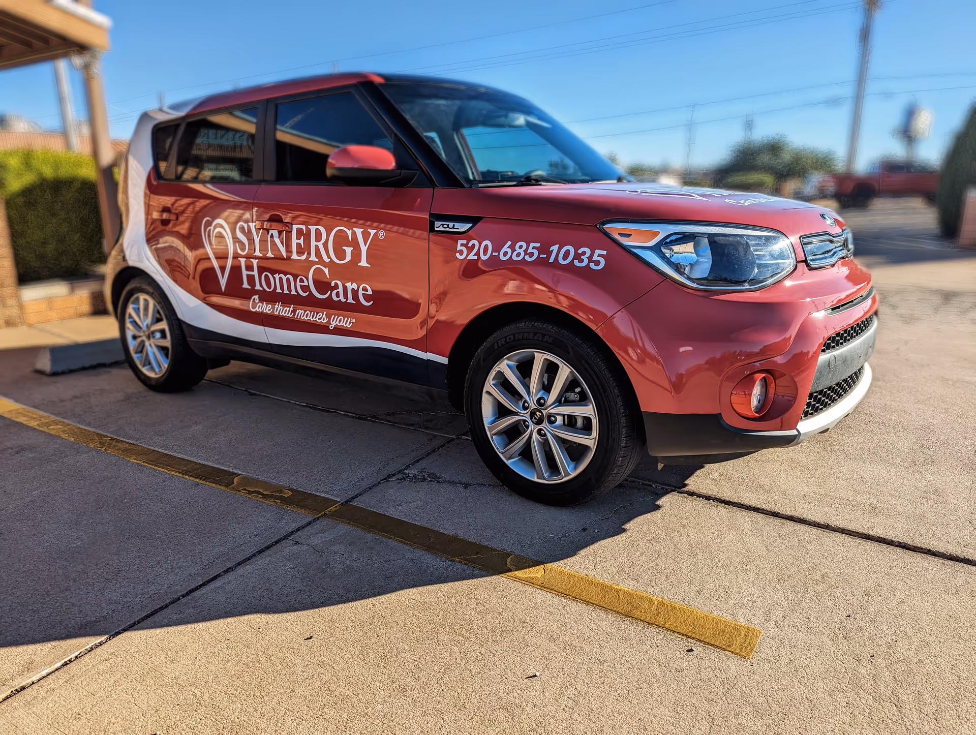 Red Synergy HomeCare van with logo parked in a sunny lot.