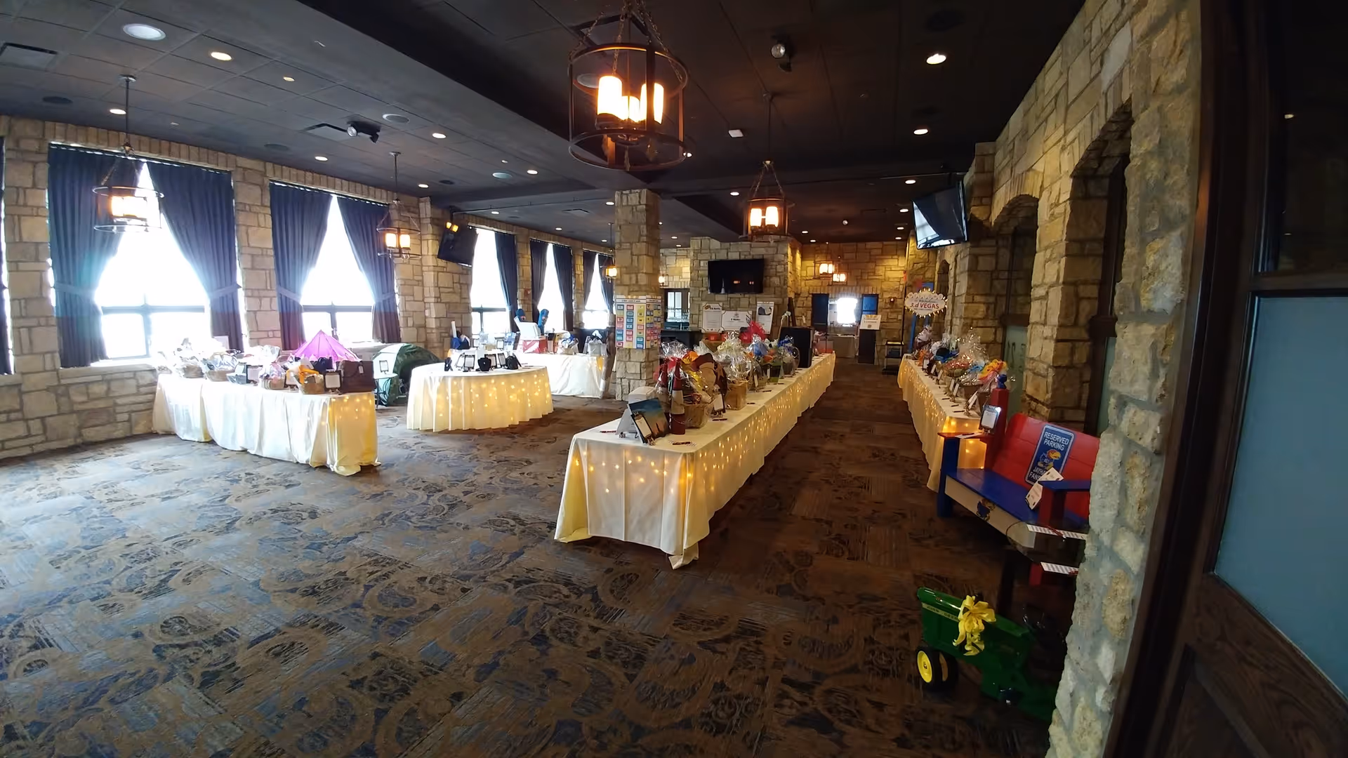 Interior banquet hall with long, decorated tables, warm lighting, and stone walls.