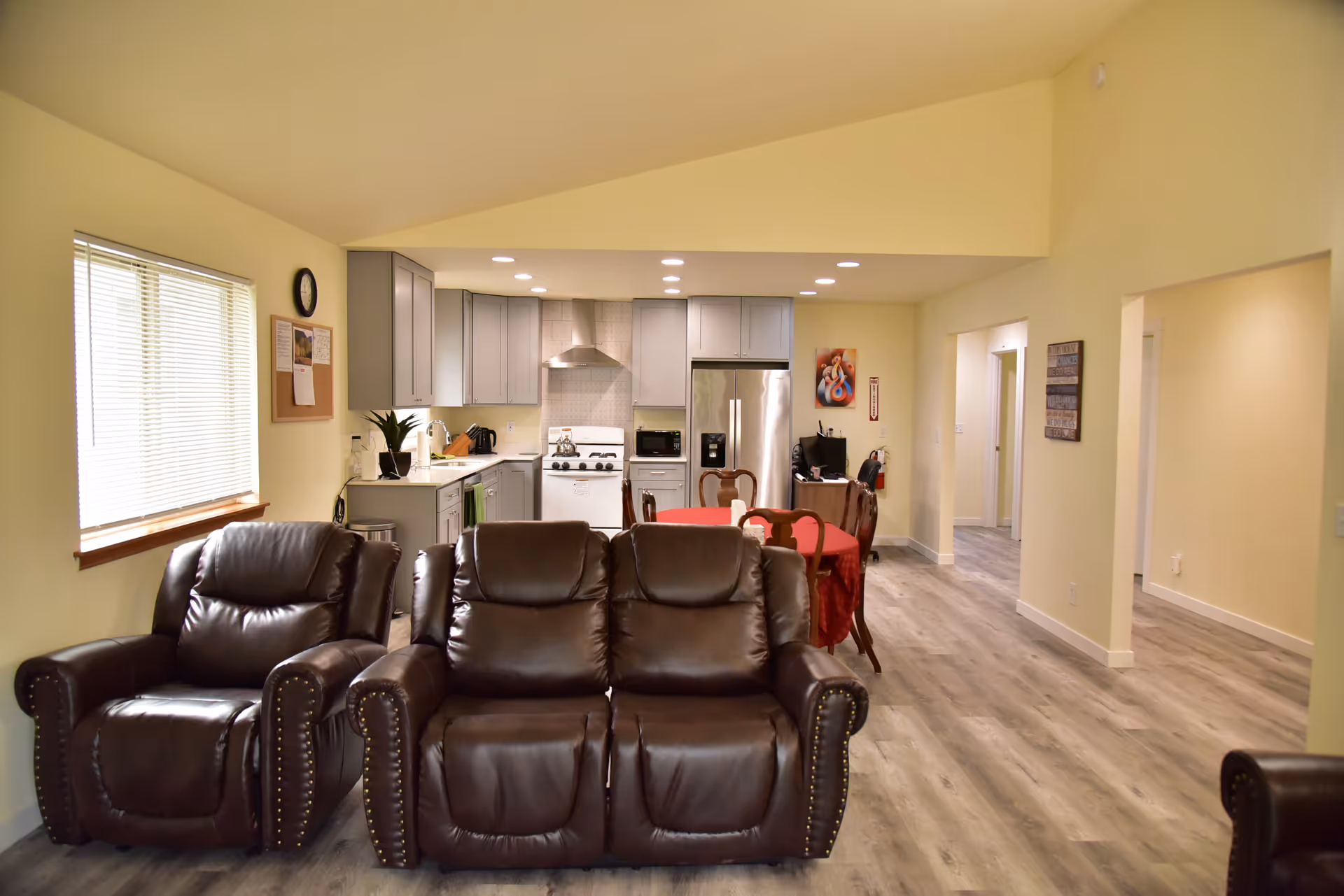 Open-plan living area with leather sofas, a dining table, and a kitchen in the background.