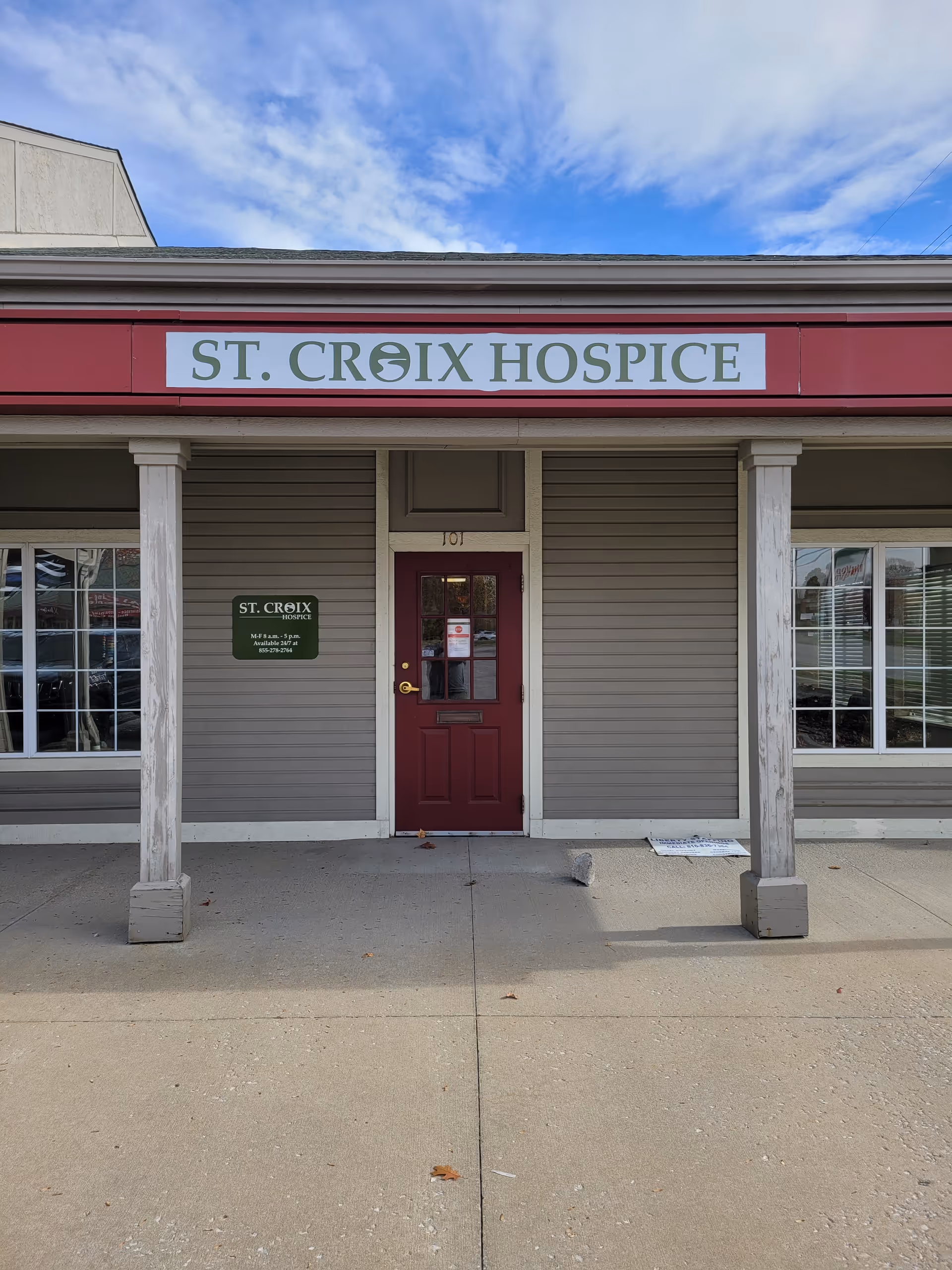 Exterior view of St. Croix Hospice entrance with a red door and sign.
