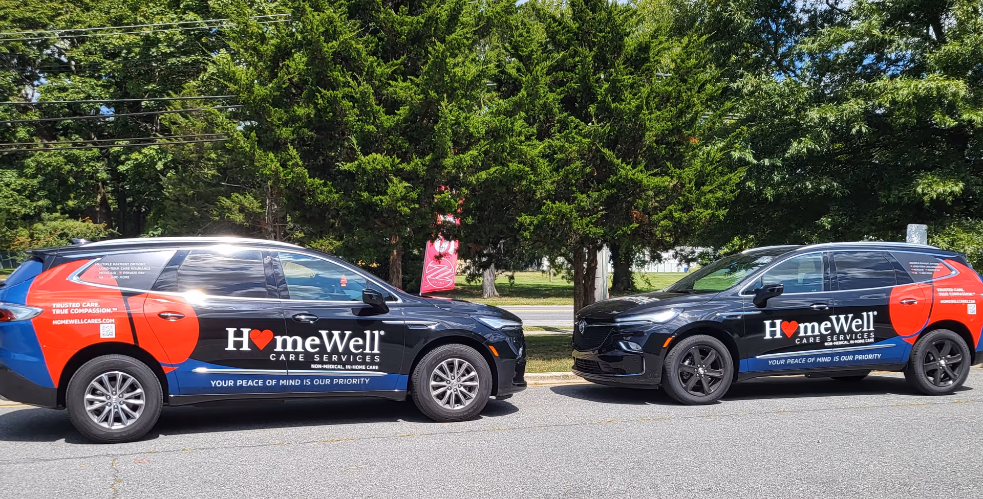 Two HomeWell Care Services vans parked along a tree-lined street.
