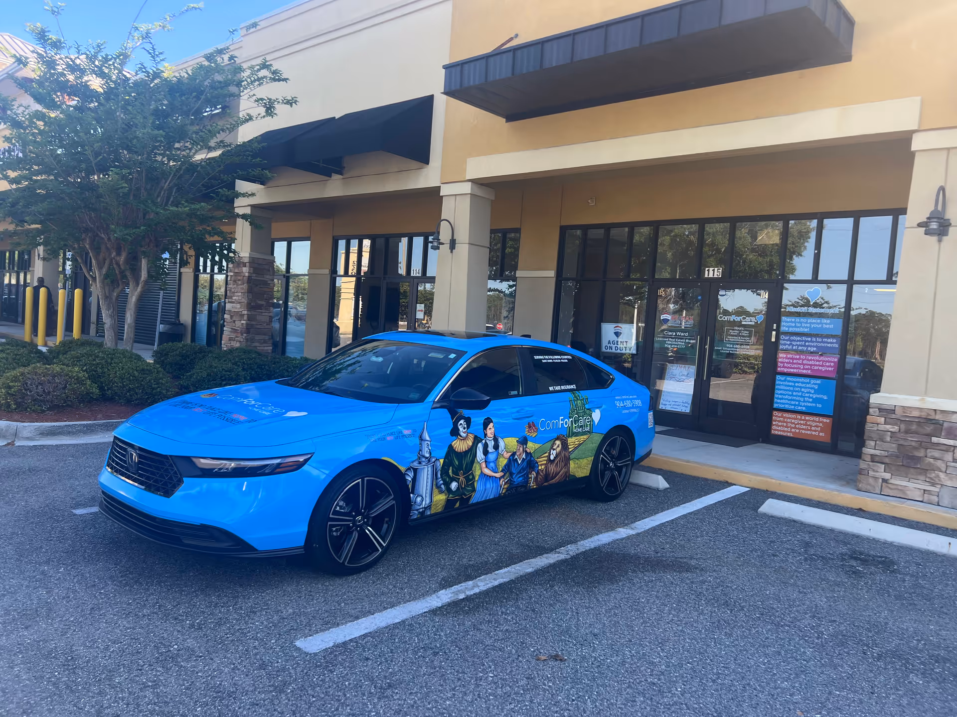 Bright blue branded car parked outside the ComForCare Home Care building entrance.