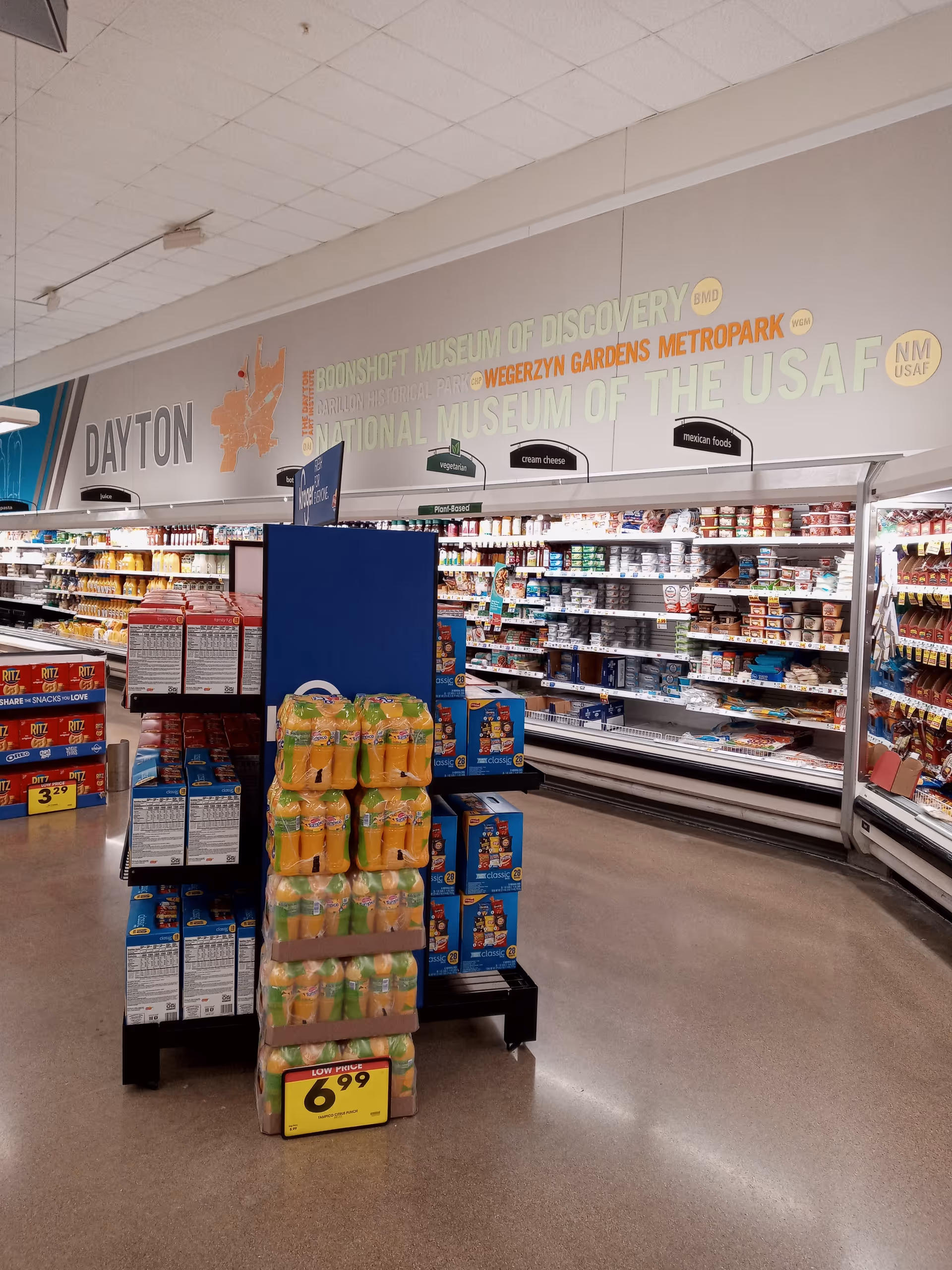 Inside a Kroger store, grocery aisles and overhead signage are visible.