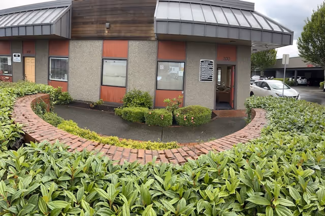 Exterior view of Amada Senior Care facility with curved brick walkway and shrubs.