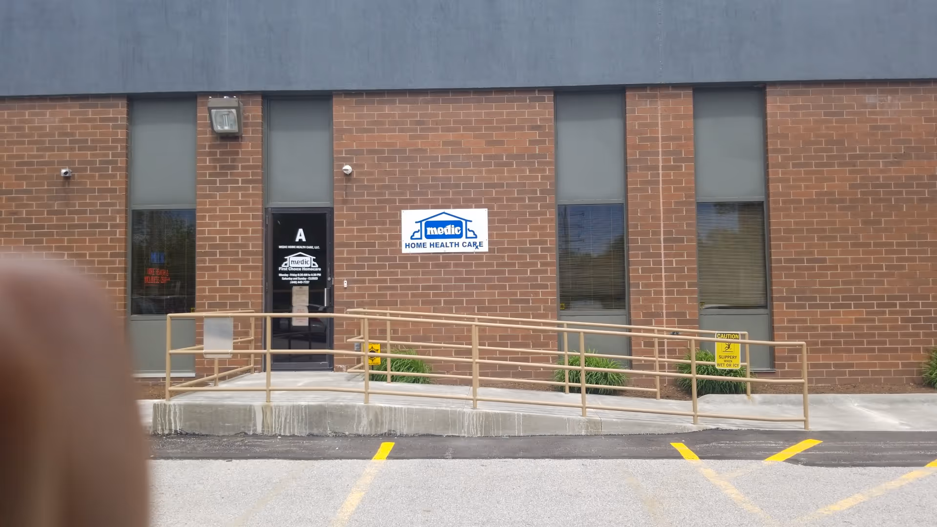 Brick building exterior with front entrance, wheelchair ramp, and a blue sign.