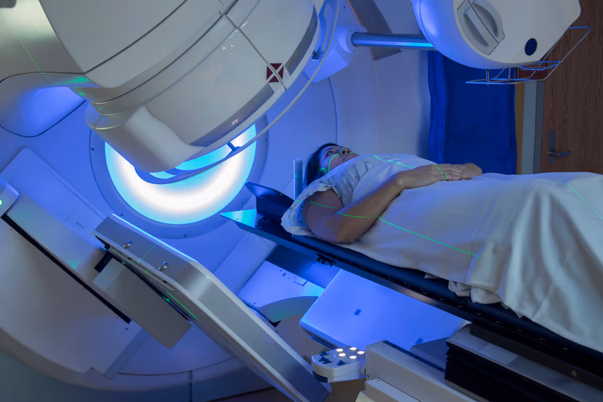 Patient lying on an MRI table inside a blue-lit medical imaging machine.