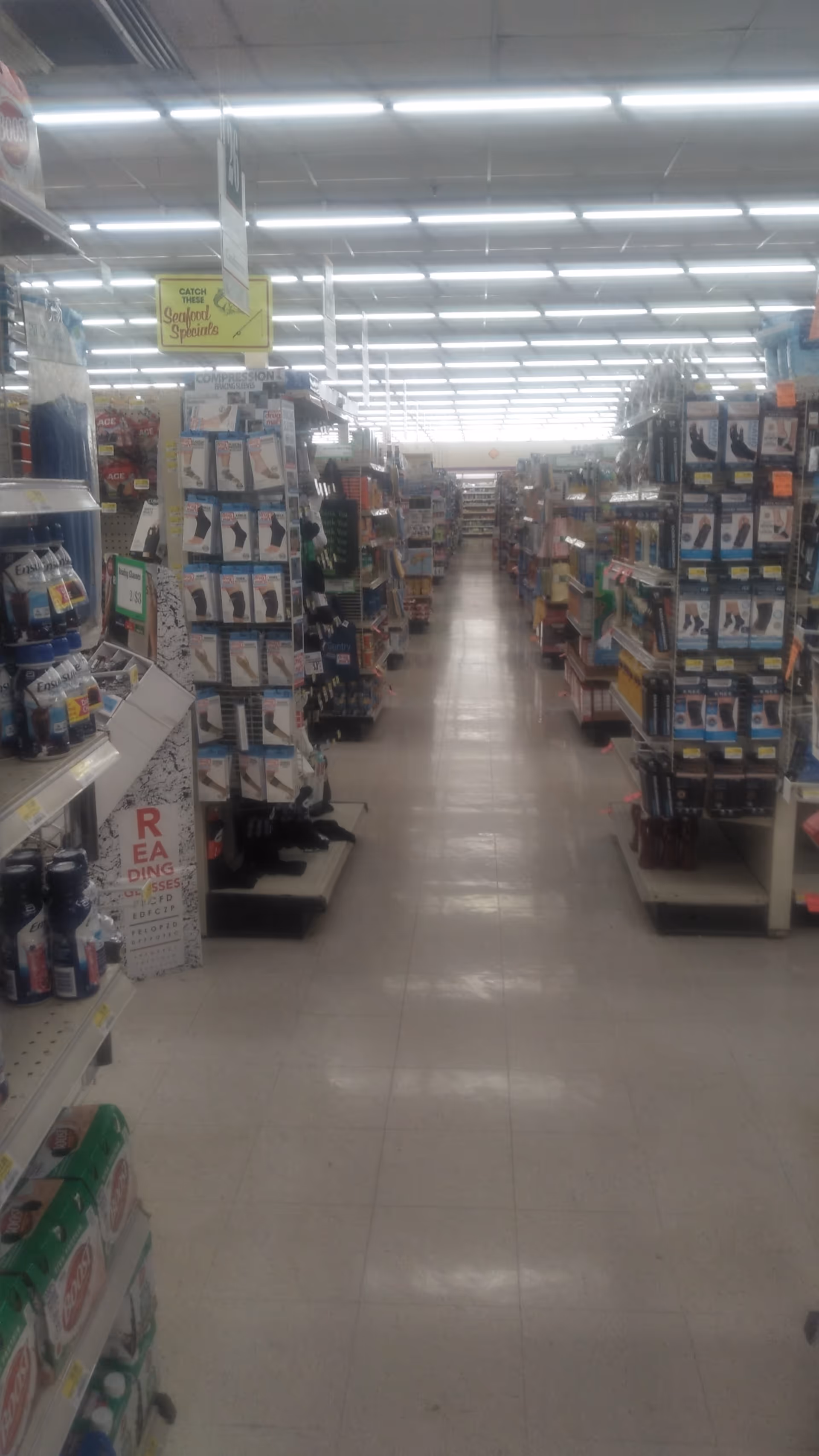 A long aisle inside a discount drugstore, with shelves stocked on both sides and fluorescent lighting.