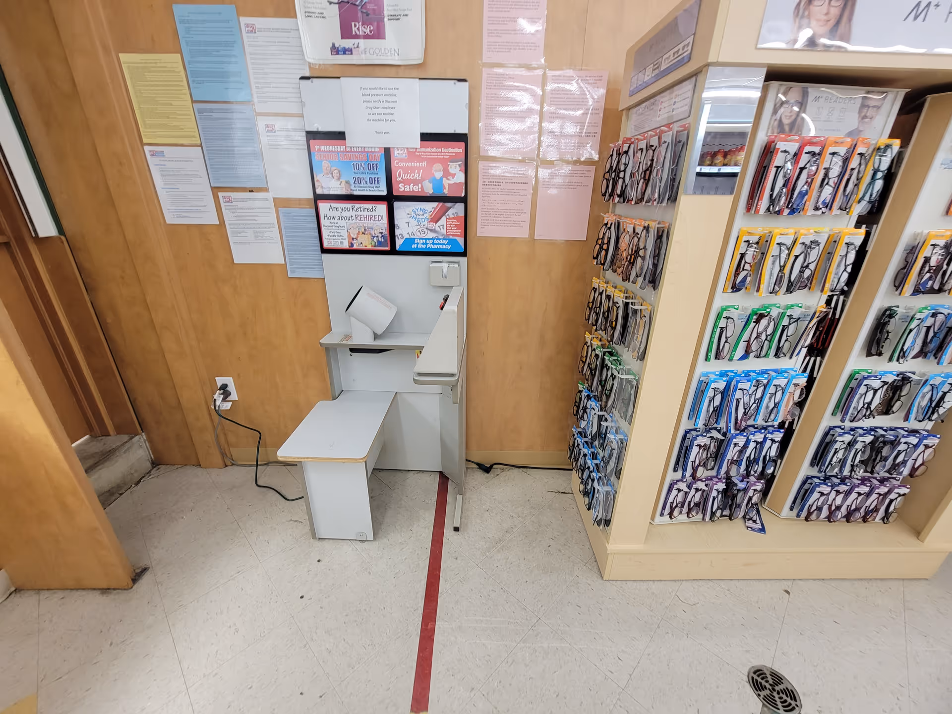 Interior of Discount Drug Mart with a small checkout desk and eyewear display