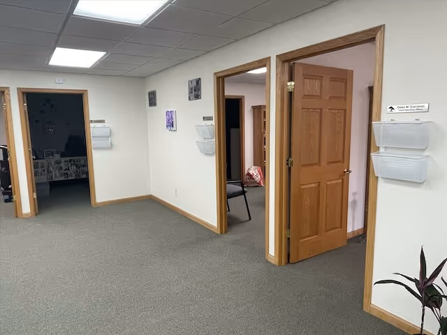 Hallway at Serenity Point Hospice with open doorways and wall-mounted organizers.