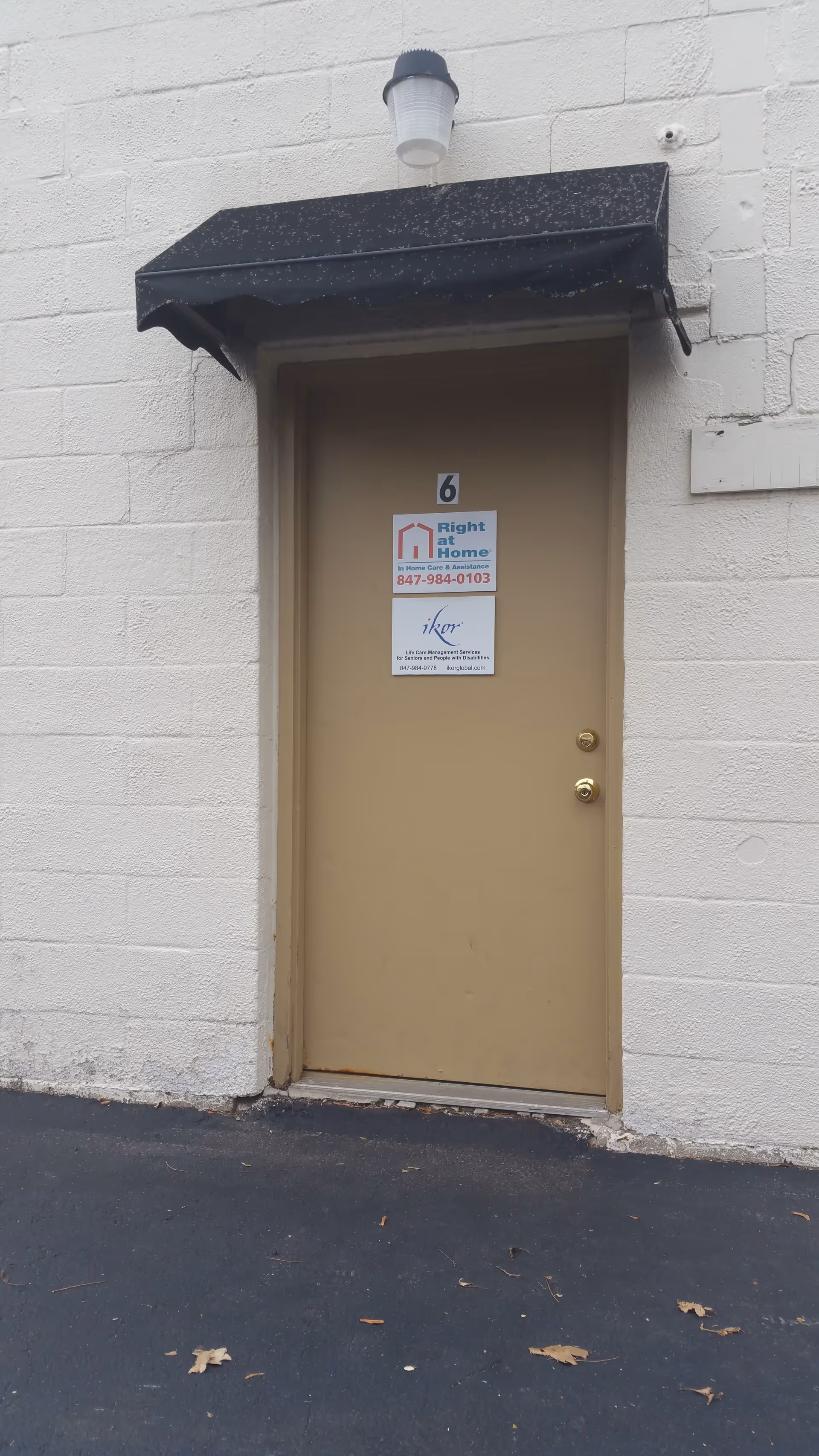 Exterior view of a facility entrance with a beige door and black awning.