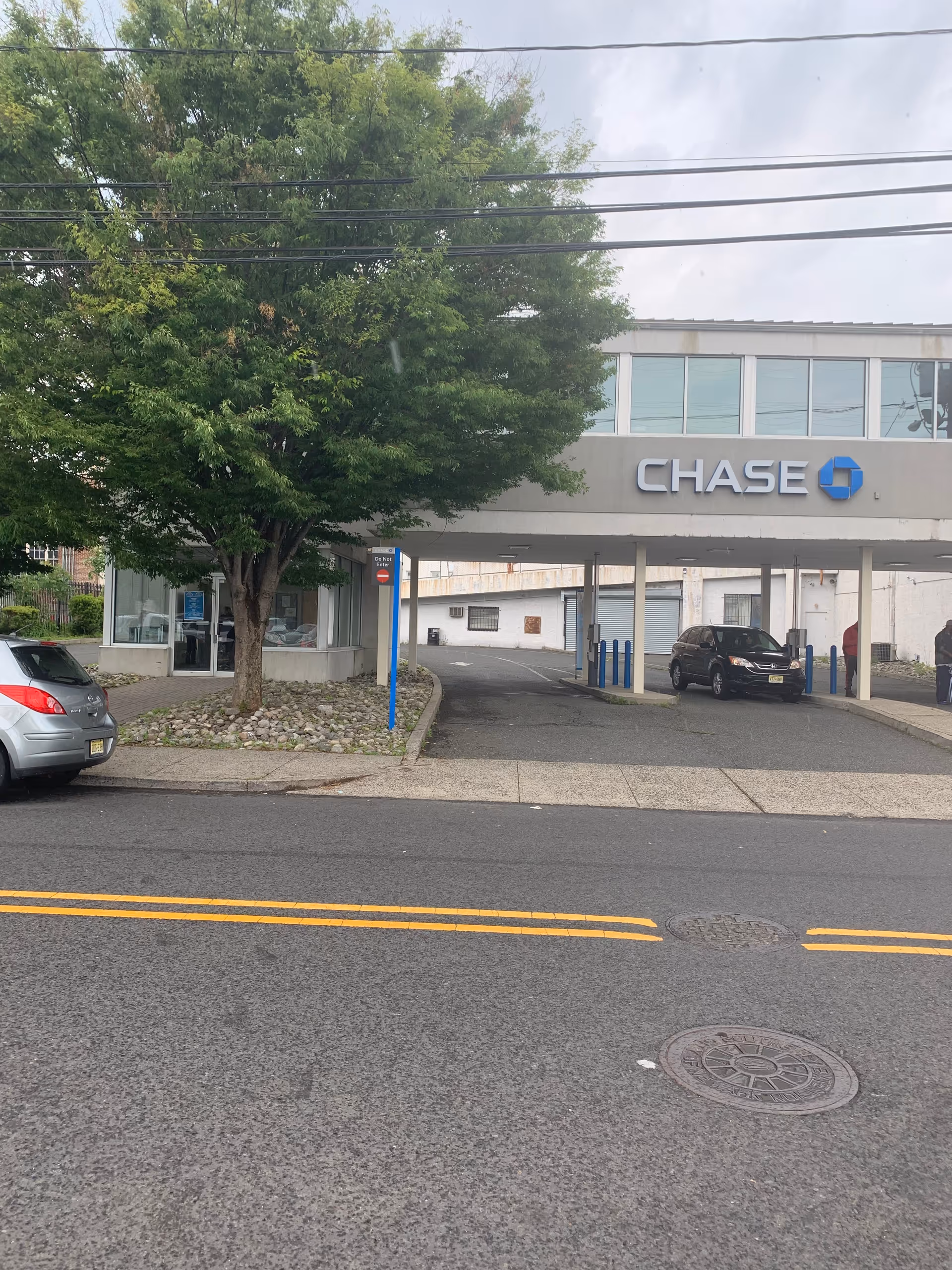 Chase Bank building with a drive-through overpass and parked cars along the street.