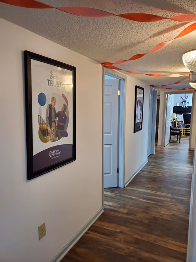 A hallway in a senior living facility decorated with orange streamers and framed posters.