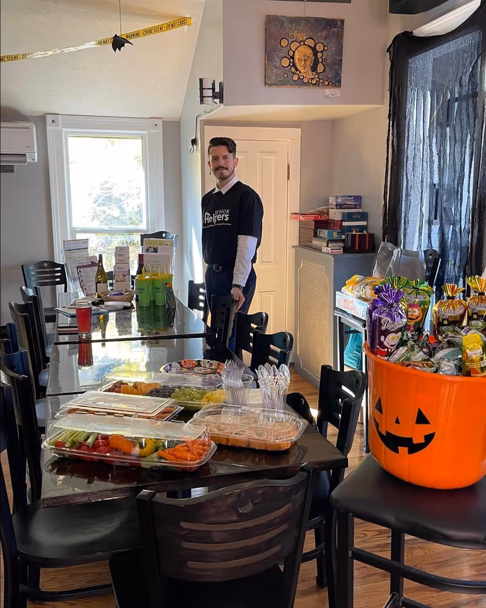 Staff member stands in dining room beside a Halloween treat table.