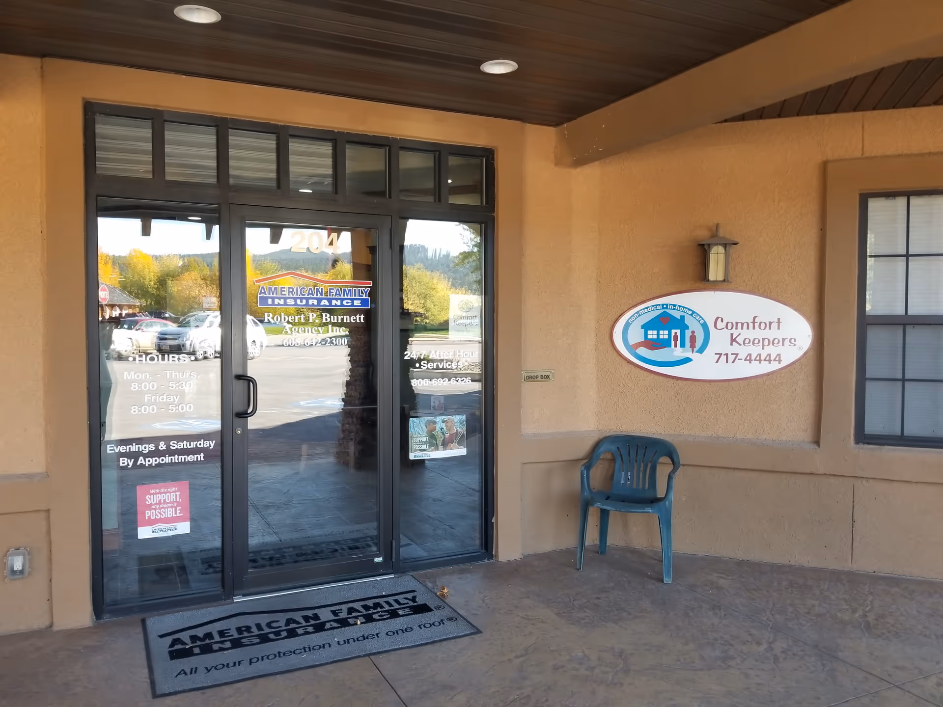 Exterior view of Comfort Keepers Home Care entrance with glass doors and a chair outside.