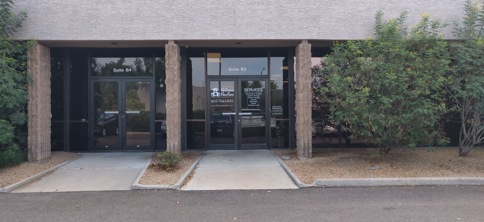 Exterior view of a building entrance with glass doors and stone columns.