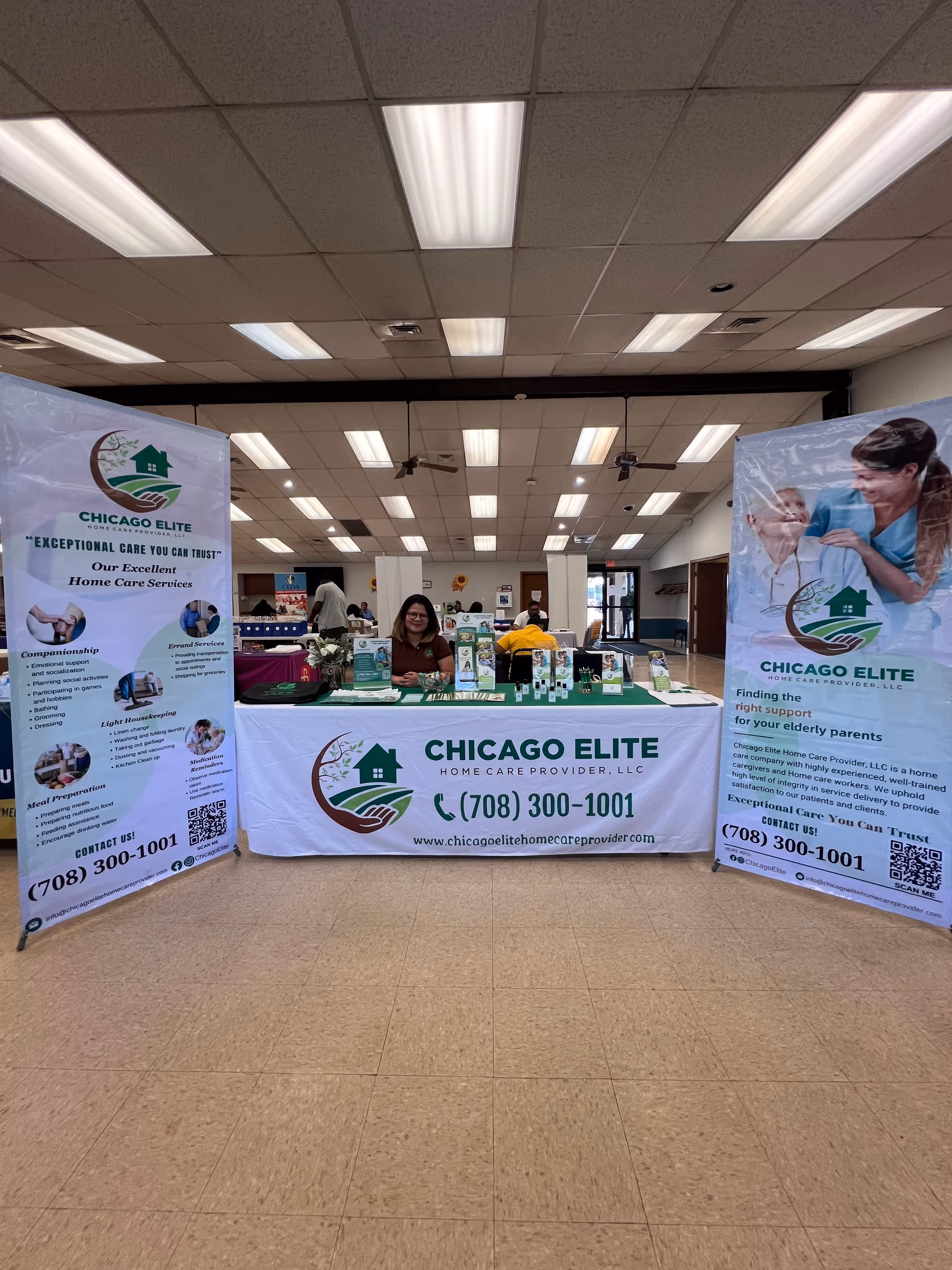 Indoor exhibition booth for Chicago Elite Home Care Provider with banners and a staff member.