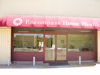 Storefront with pink awning reading Encompass Home Health over glass doors and windows