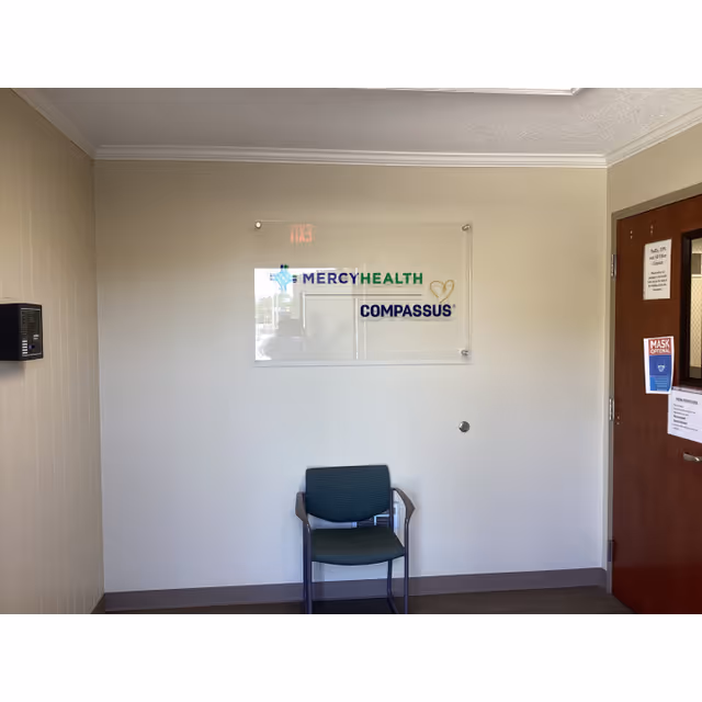 Minimal interior lobby area with Mercy Health Compassus sign and a lone green chair.