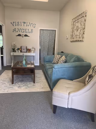 Cozy lounge area in a Visiting Angels senior home care facility with sofa and coffee table.