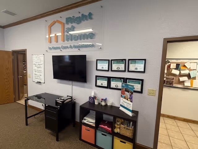Lobby area with Right at Home sign, wall certificates, TV, and storage cabinet.