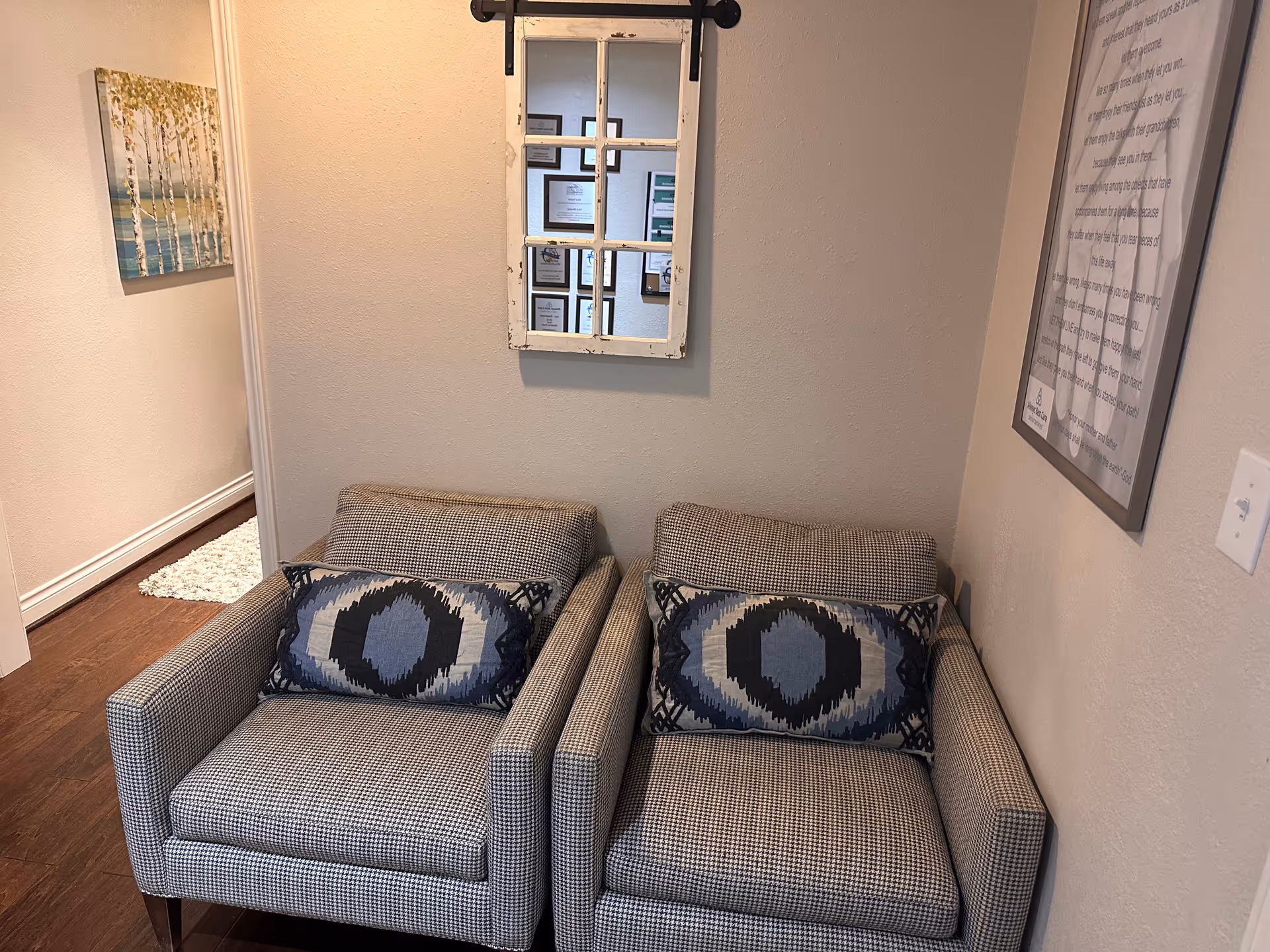 Two gray checkered armchairs in a hallway seating nook with wall art.