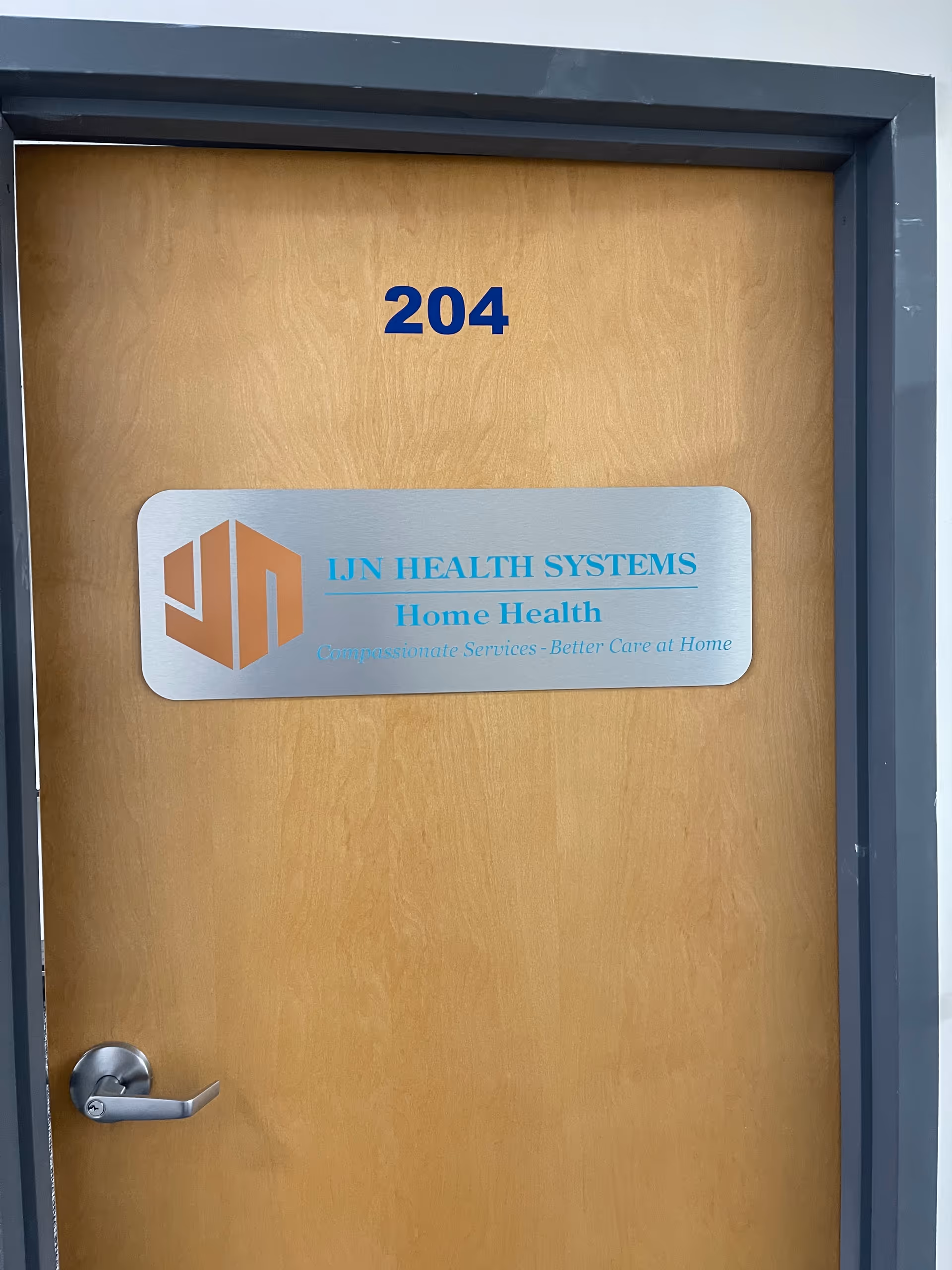 A wooden interior door labeled 204 with an IJN Health Systems Home Health sign.