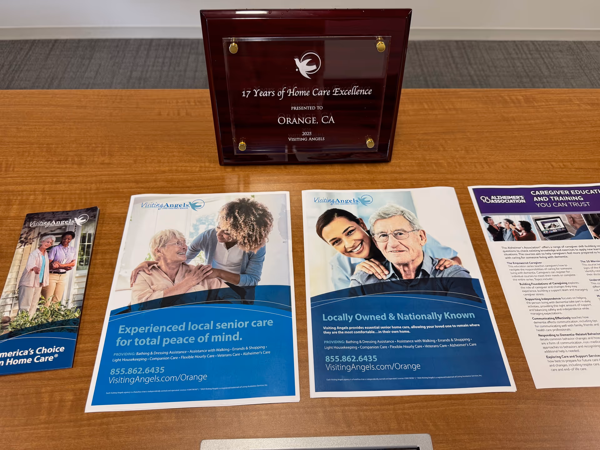 Wooden table with Visiting Angels brochures and a plaque display.