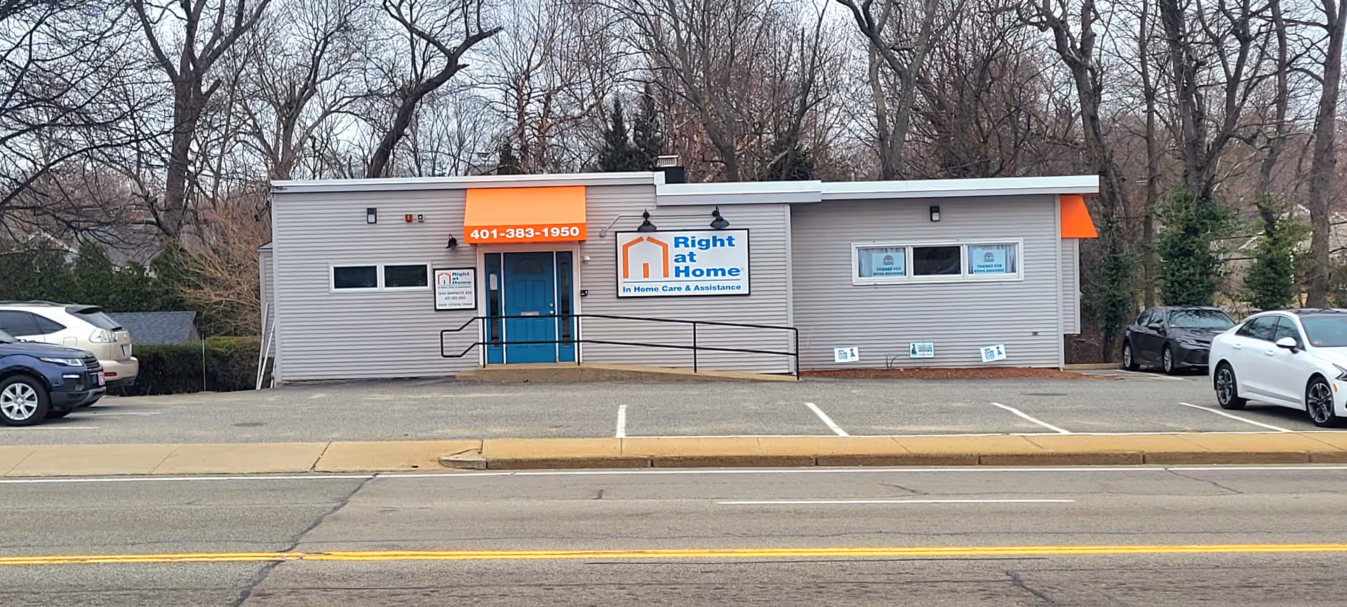 Front view of a Right at Home office building with parking lot and leafless trees.