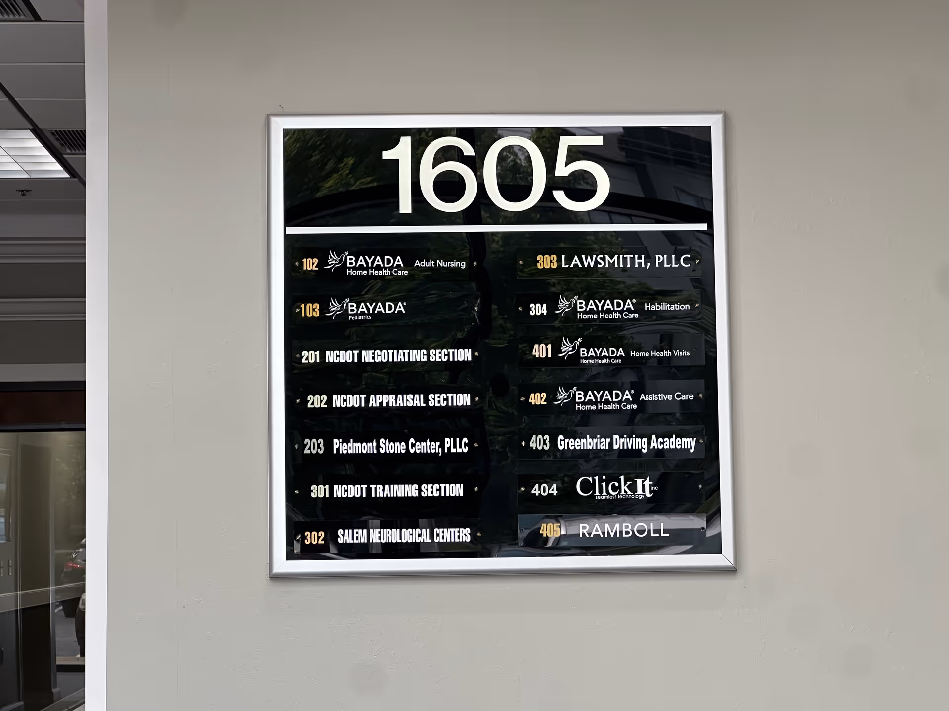 Large interior directory plaque listing suite numbers and tenant names on a wall.