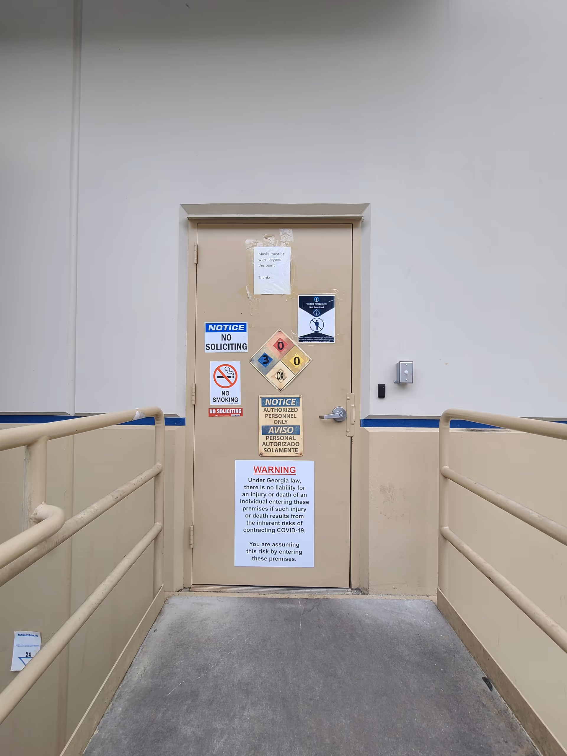 Beige door with multiple warning signs in a corridor at an Apria Healthcare facility.