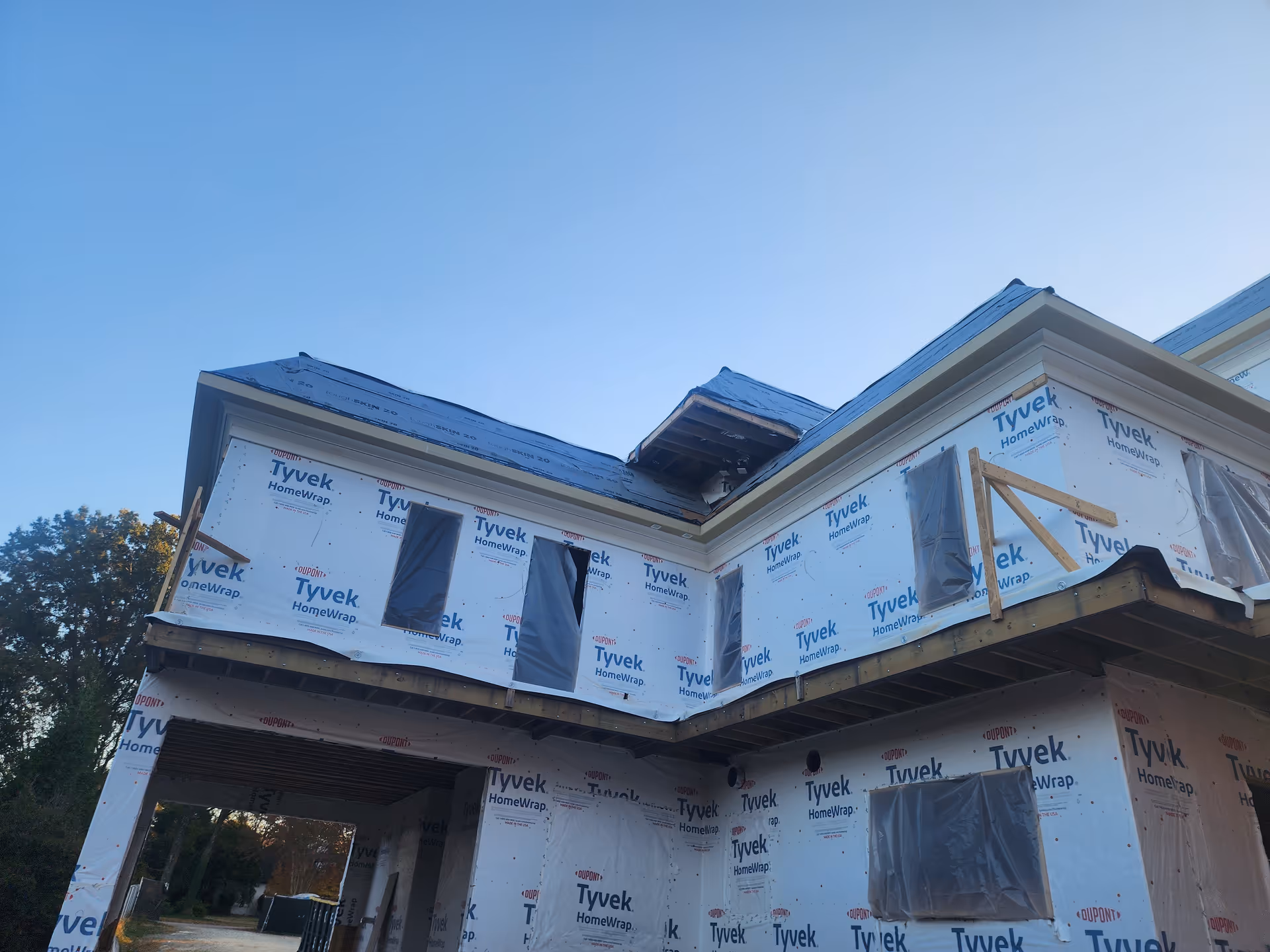 Under-construction two-story building wrapped in Tyvek with exposed framing and windows.