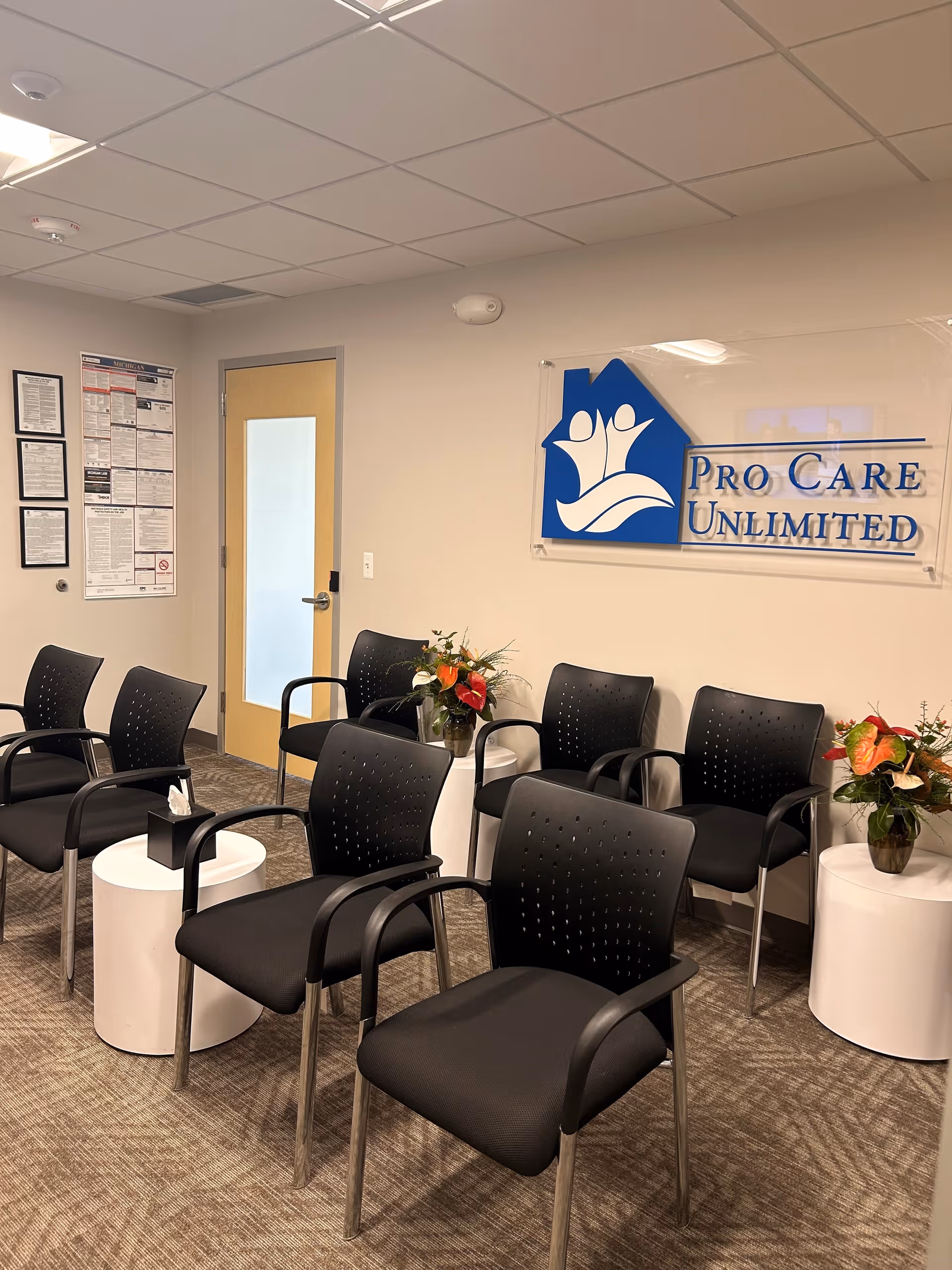 Interior waiting area with black chairs, white tables, and a Pro Care Unlimited sign.
