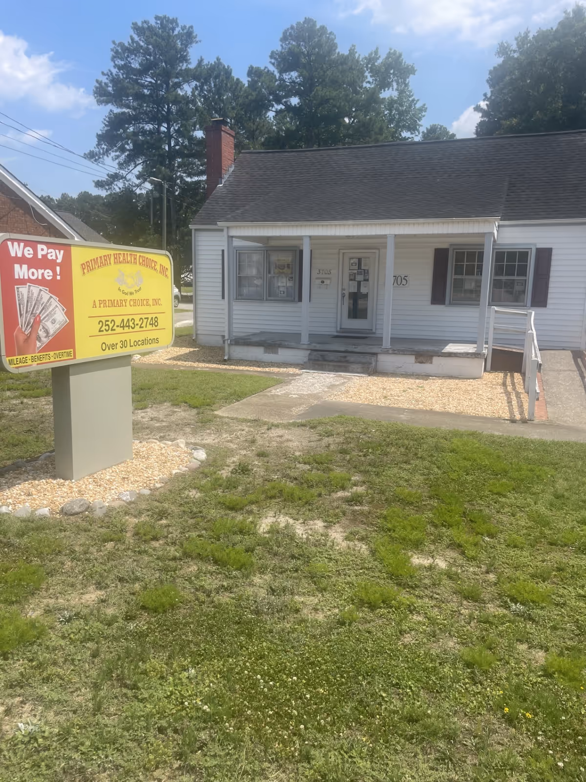 Small white front-building with porch and a large yellow sign advertising Primary Health Choice.