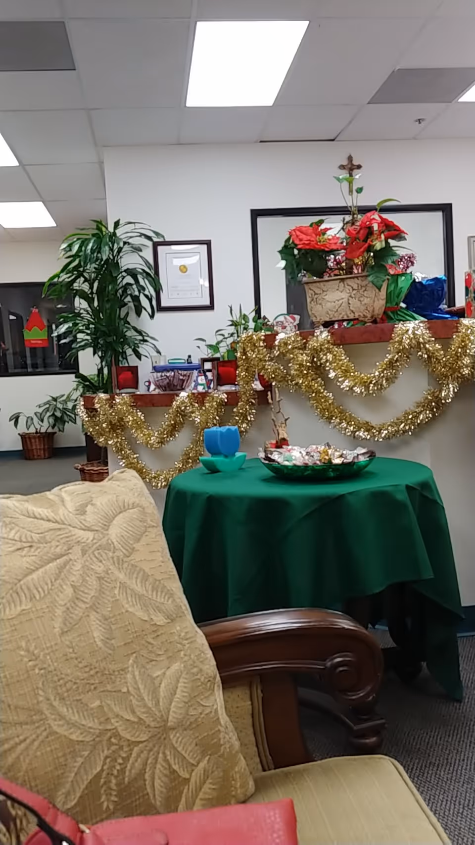 Indoor lounge with holiday decorations, plants, and a green-draped round table.