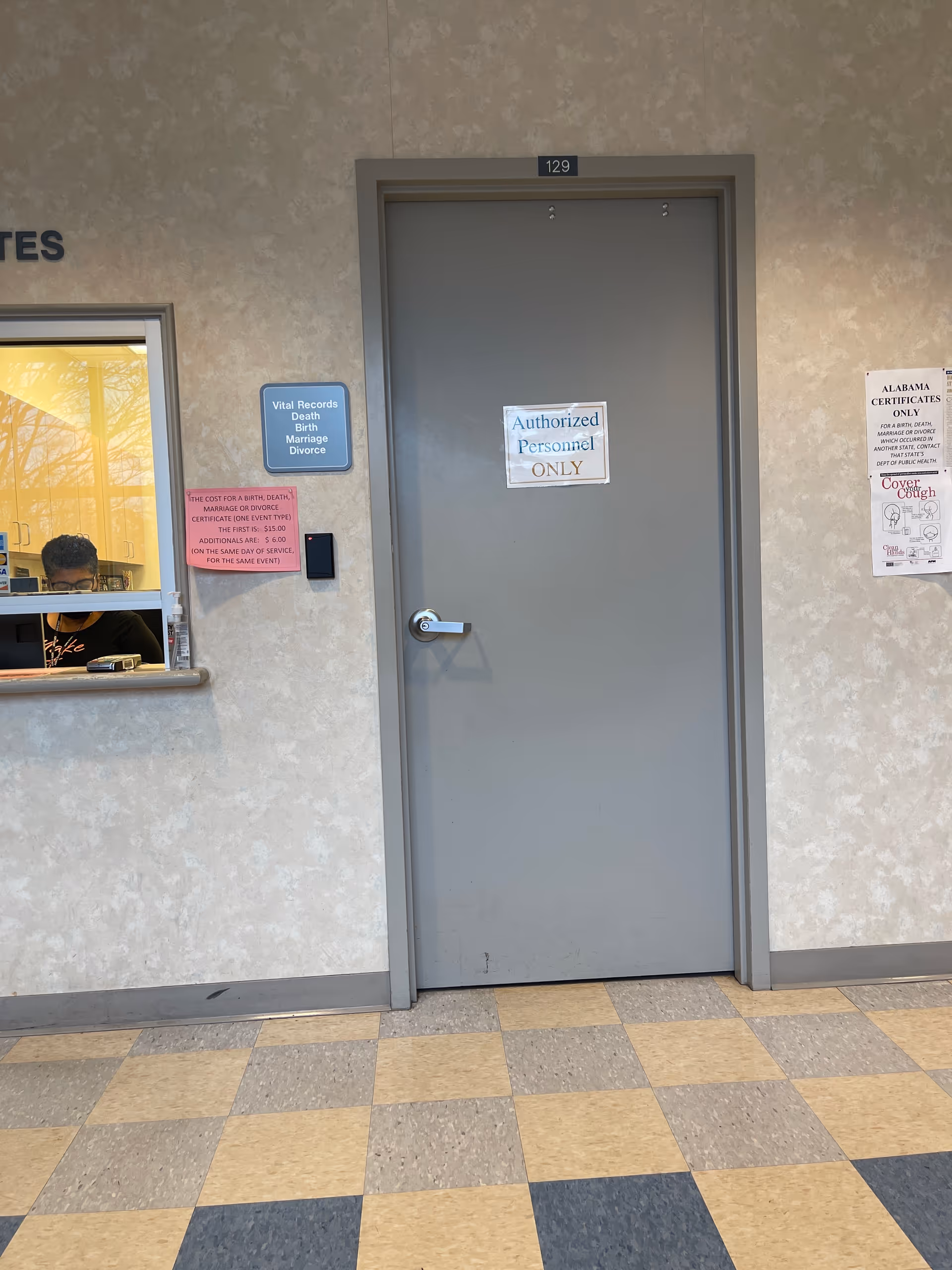 Gray door labeled Authorized Personnel ONLY flanked by a reception window inside a Health Department hallway.