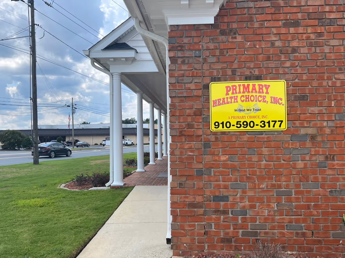 Brick building exterior with a bright yellow Primary Health Choice sign near the entrance