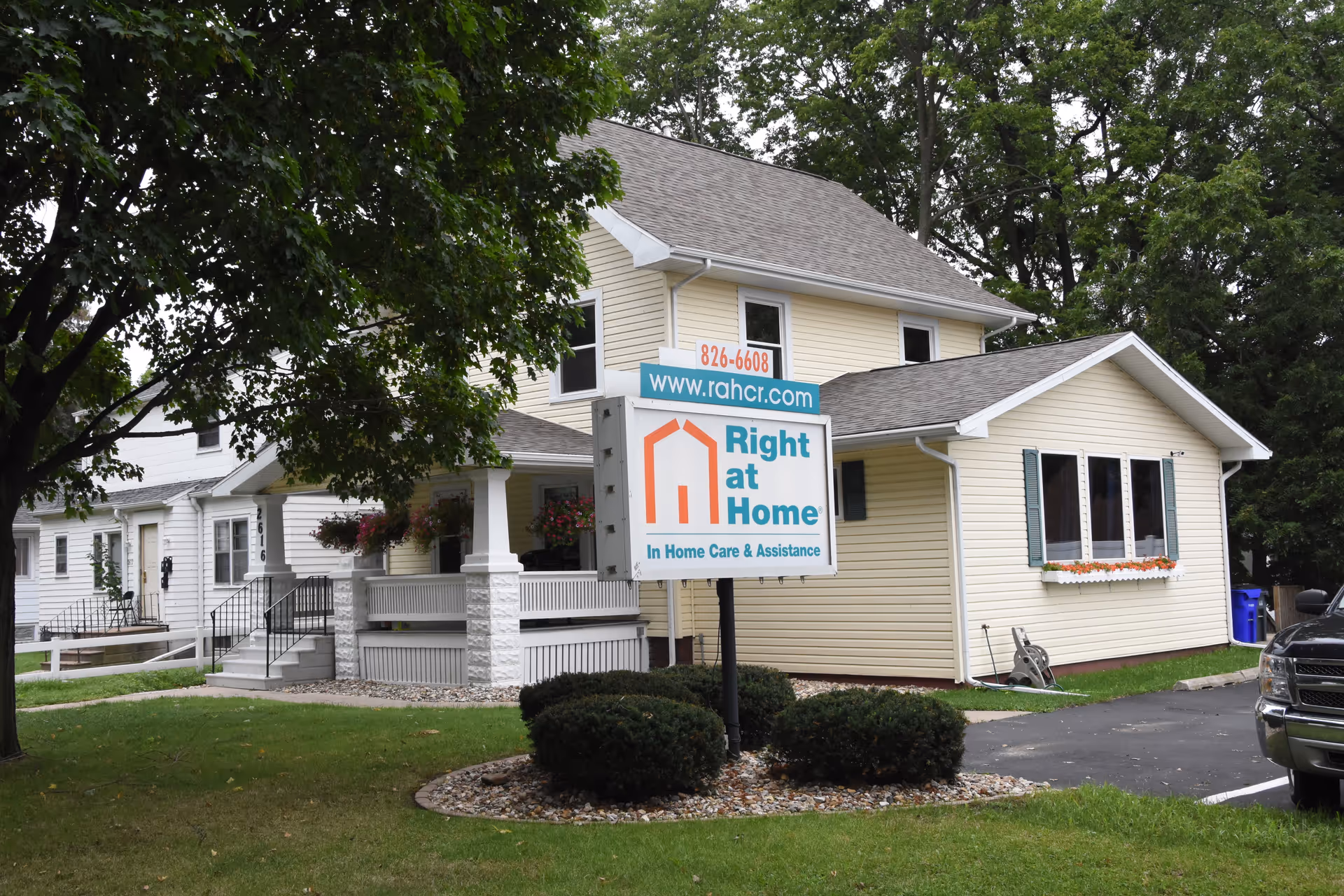 Two-story beige senior care building with a prominent Right at Home sign in the front yard