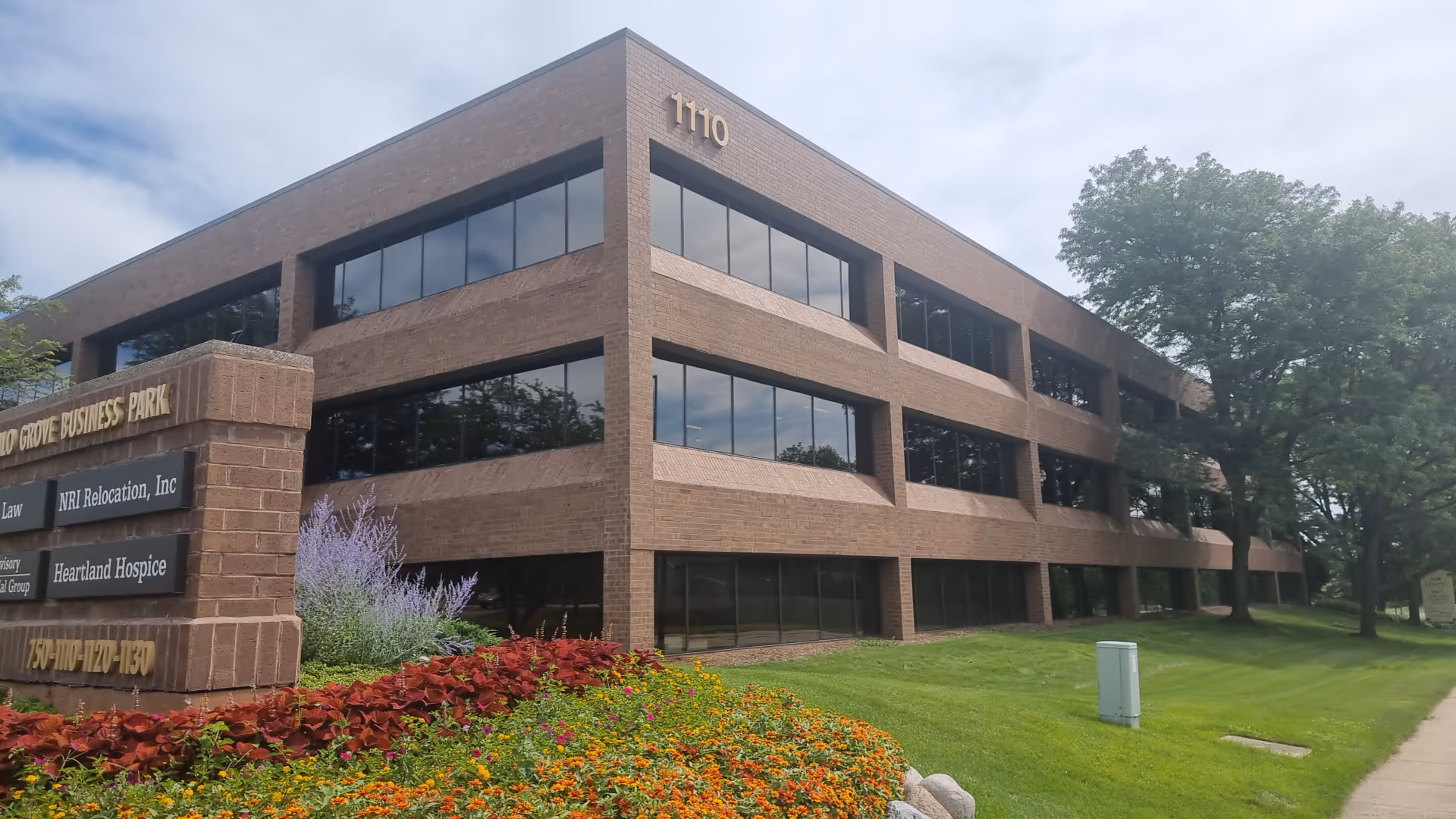 Brick, multi-story office building with large windows and a landscaped front lawn.