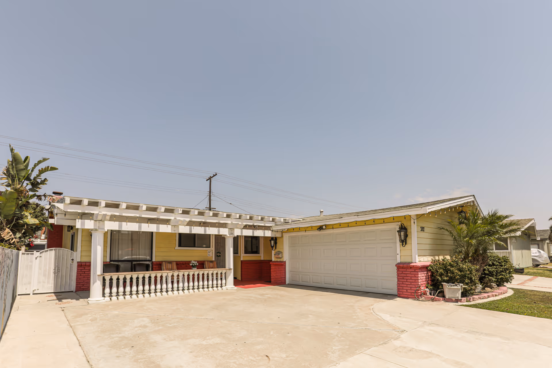 Single-story retirement home facade with a white pergola, front porch, and two-car garage.
