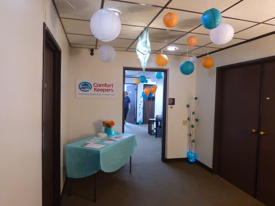 Interior hallway of Comfort Keepers Home Care with a decorated table and hanging lanterns.