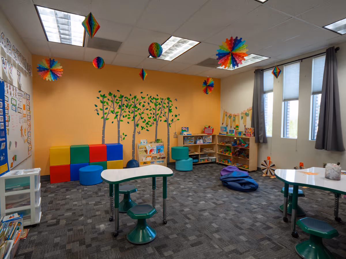 Bright children's activity room with toys, tables, and a wall mural inside a facility