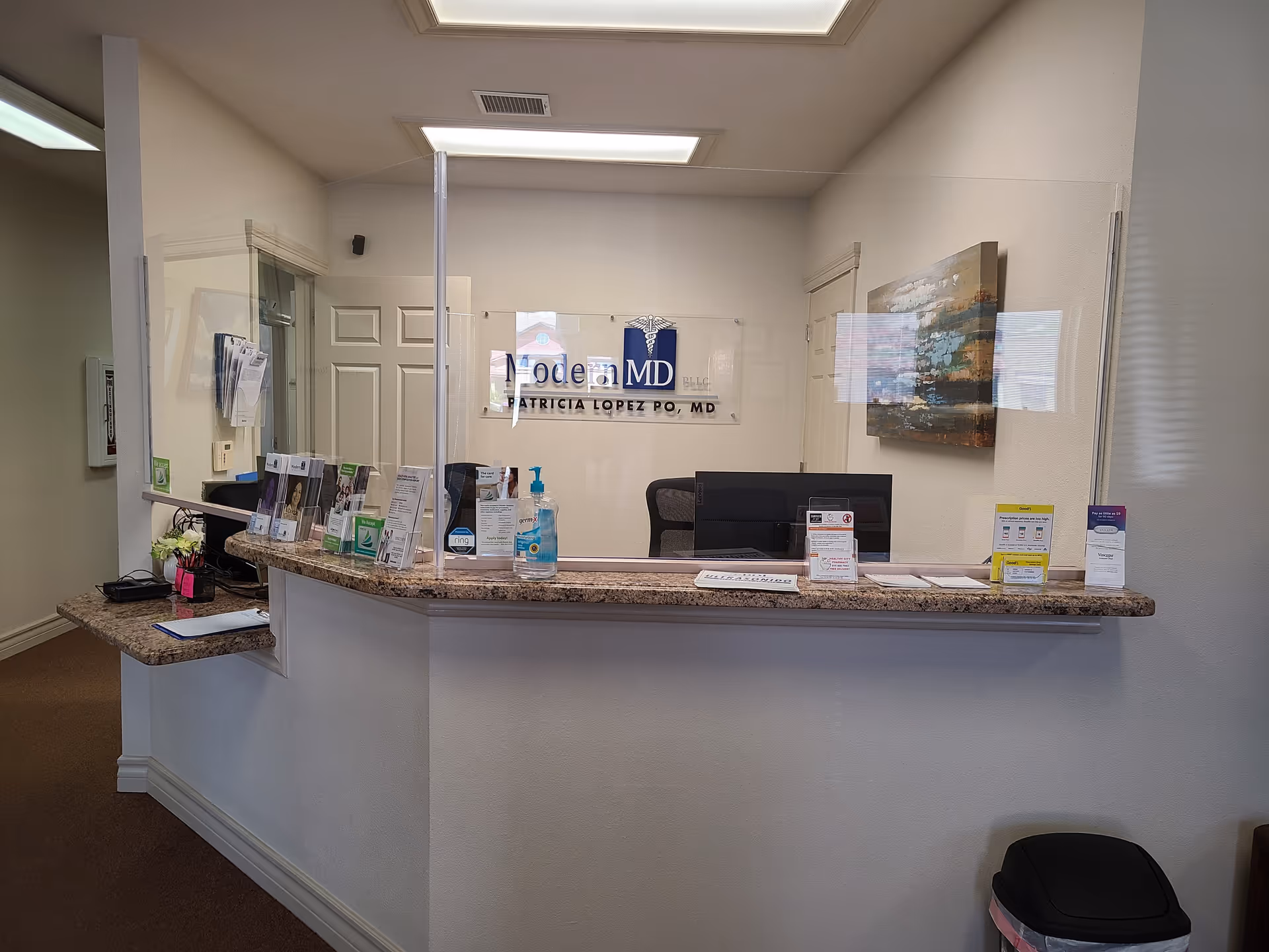 Reception desk with brochures and sanitizer in a Modern MD lobby.