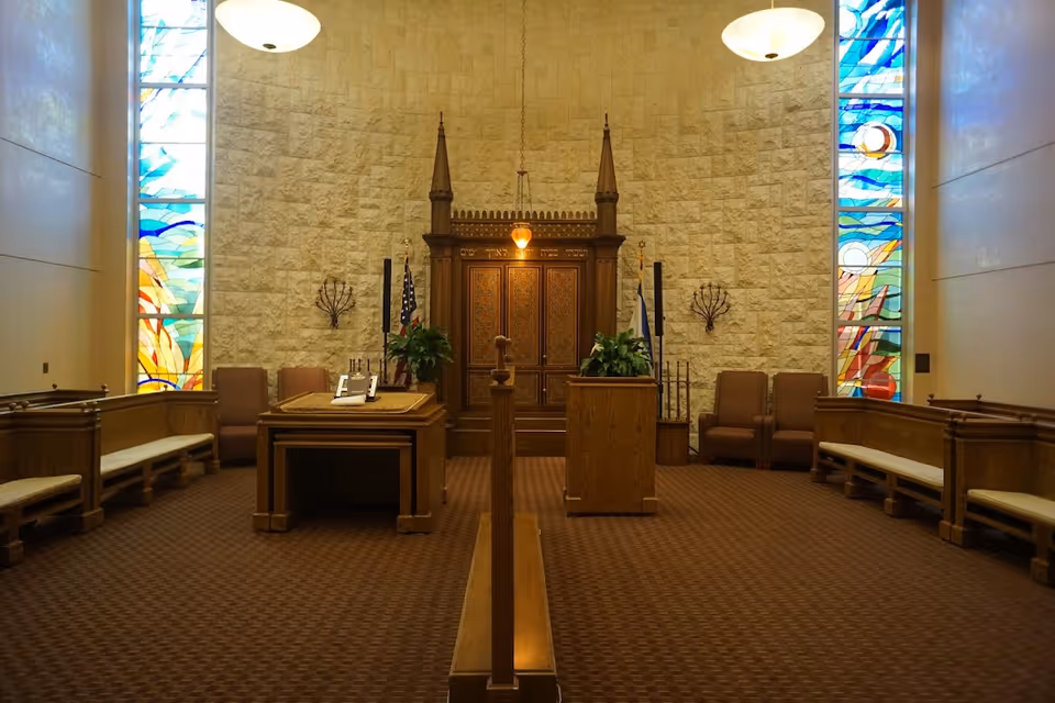 Interior chapel in a senior living facility with pews, lectern, and stained glass