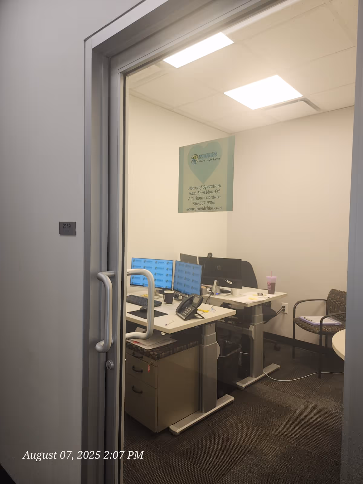 Small office inside a senior care facility with desks, monitors, and a sign on the wall.