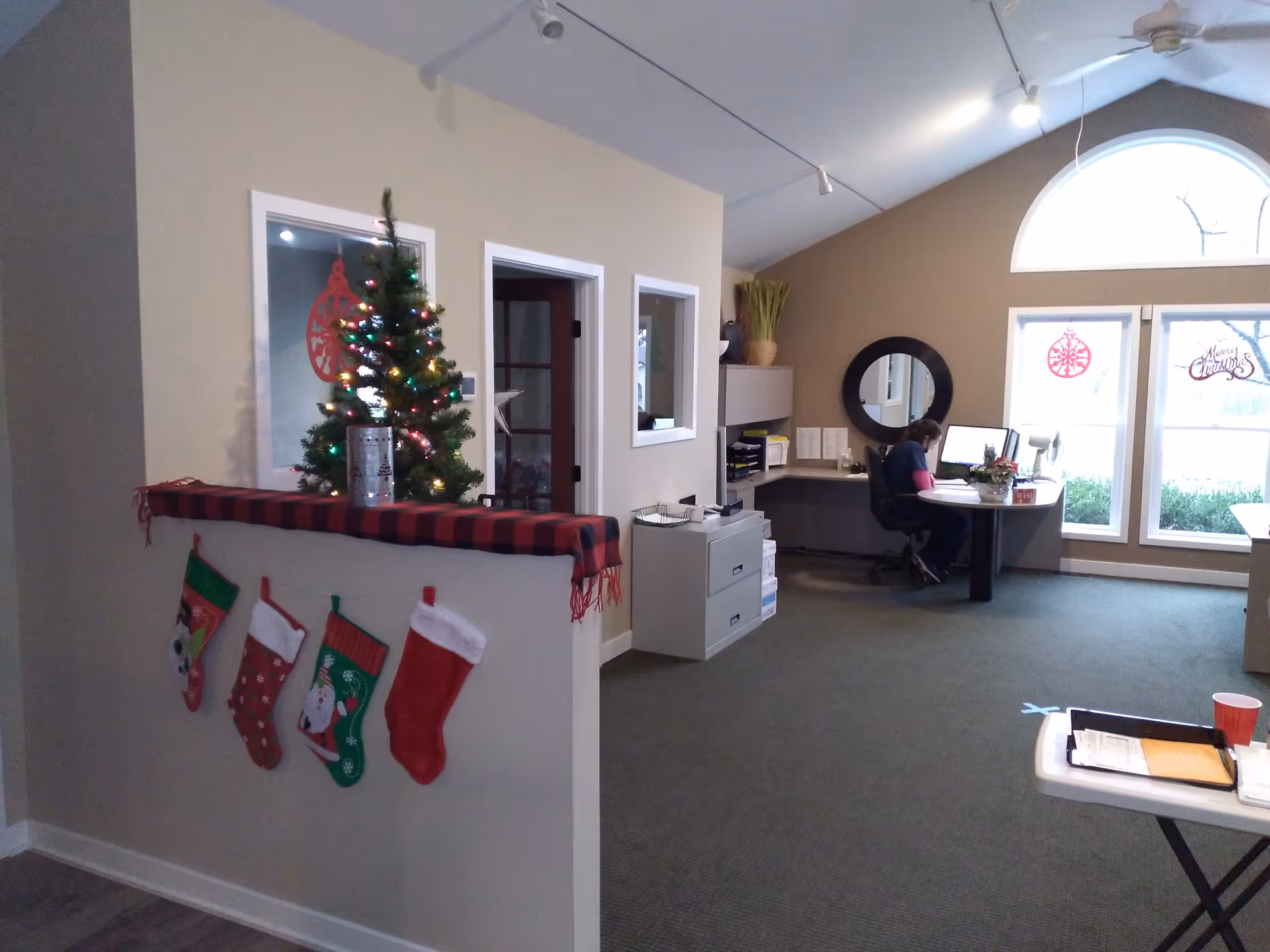 Reception area with Christmas tree, stockings, and a staff member at a desk.