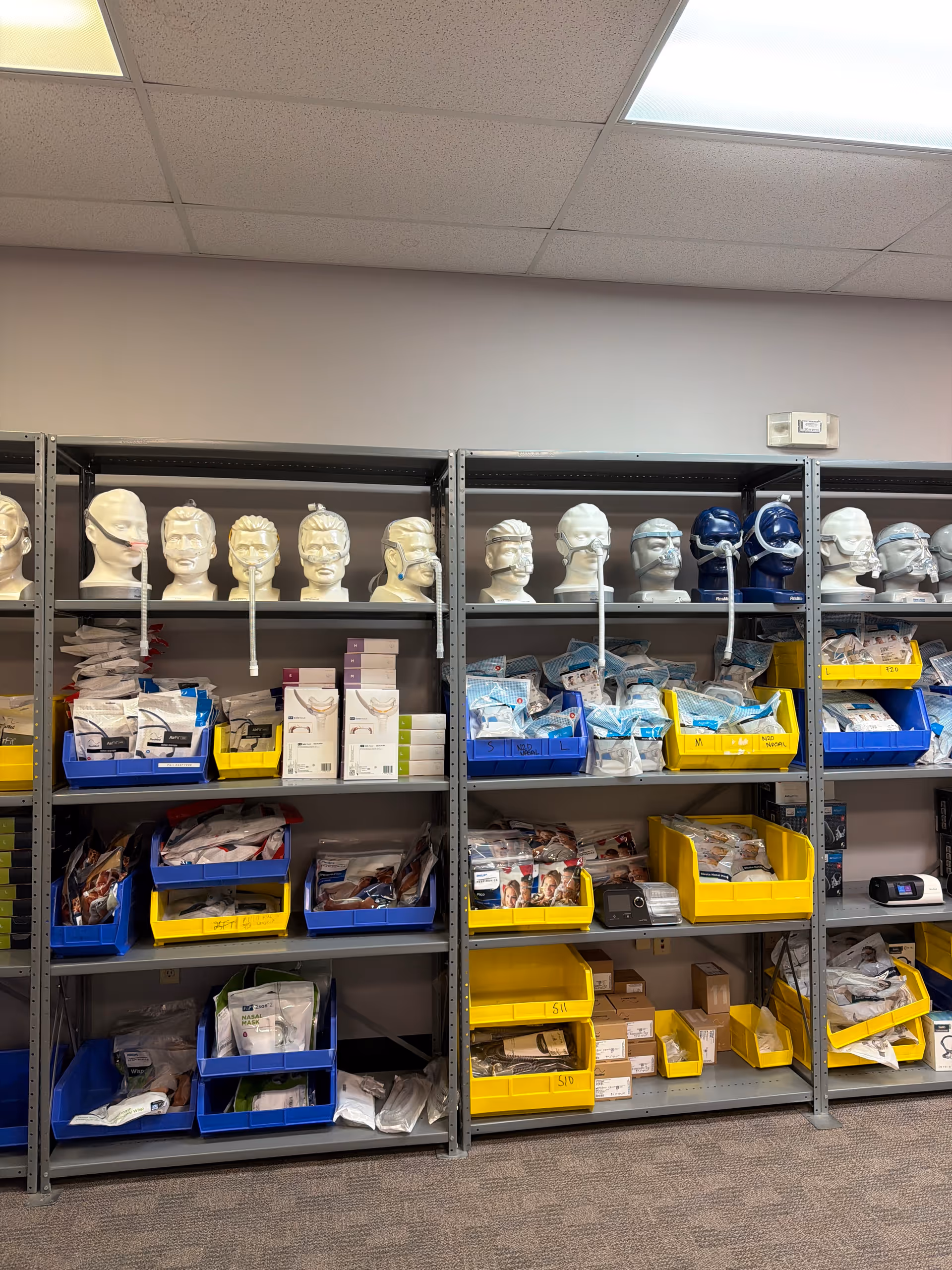 Interior storage shelves with medical supplies and mannequin heads in a facility.
